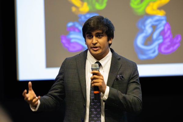 Bioinformatics master's student Rishi Misra gives his Three-Minute Thesis presentation about bats during the final round of the competition, wearing a suite that includes a necktie with a bat design.
