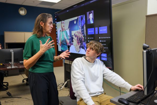 Professor Stephanie Schuckers talks with Ph.D student Weston Bondurant with a real-time deepfake generator program displayed on the monitor behind them.