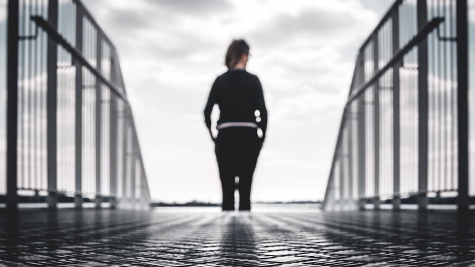 grayscale photo of woman in between gray metal railings