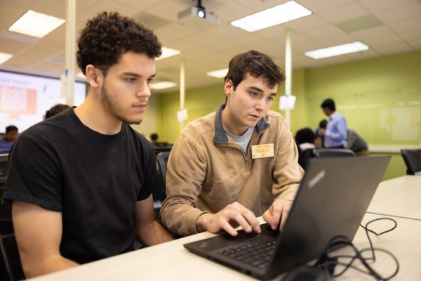 CCI student teaching assistant helps computer science student with an assignment during a TA session on a ThinkPad PC laptop.